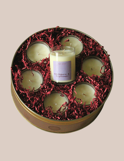 Set of candles in a decorative tin with red shredded paper